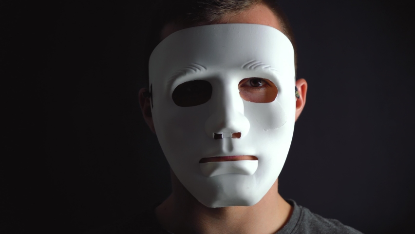 A man hides his face under a white mask | Shutterstock HD Video #1064927743