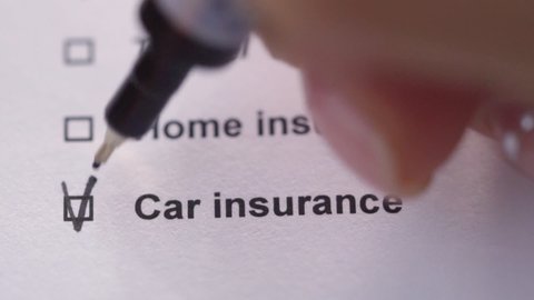 The person marks the item Car insurance with a tick. Close-up. Preparation of contract