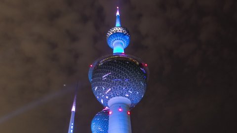 KUWAIT - CIRCA FEB 2019: The Kuwait Towers timelapse hyperlapse illuminated at night - the best known landmark of Kuwait City. Kuwait, Middle East. View with palms and cloudy sky