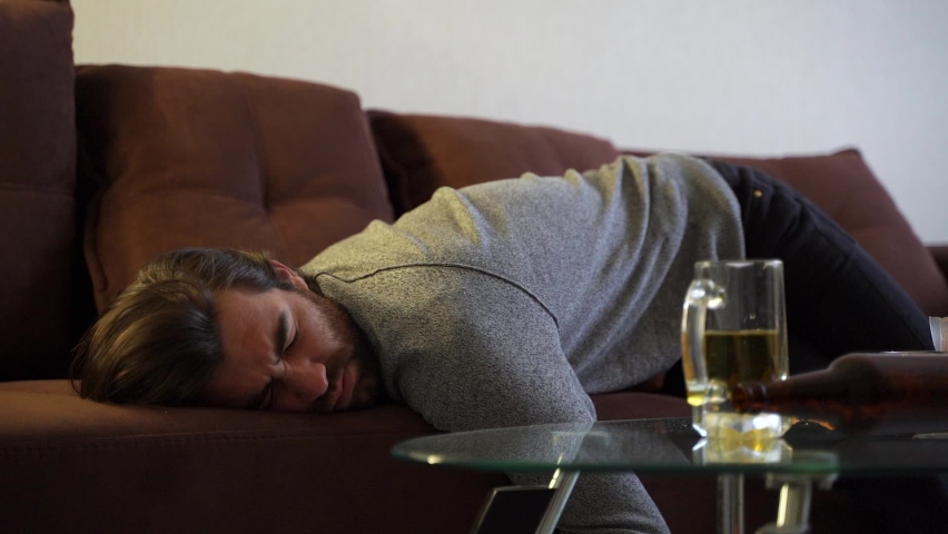 Man sleeping on sofa after party at home. Morning hangover after party. Celebrating holiday. He is napping, snores. | Shutterstock HD Video #1064947336