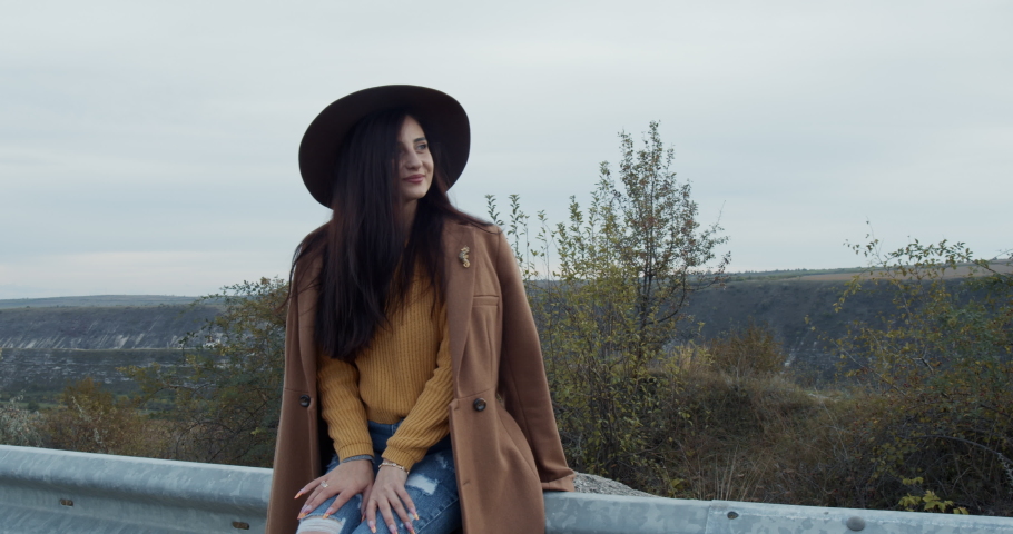 a young, rumored girl smiles and is happy on the side of the road outside the city. A girl at sunset, thoughtful and dreamy. A beautiful spring day, autumn. Slow motion.