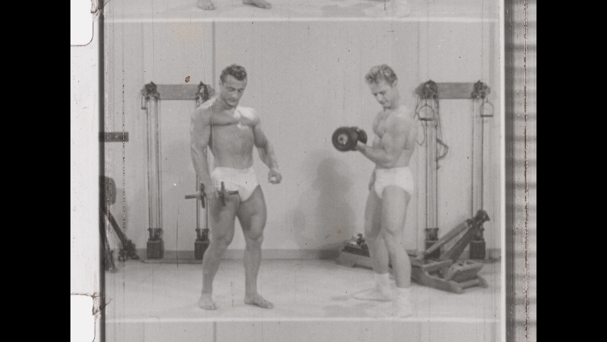 1940s Los Angeles, CA. Woman in Gym Lifts Dumbbells. She is Impressed by Two Male Body Builders Lifting Weights. 4K Overscan of Vintage Archival 16mm film Print
