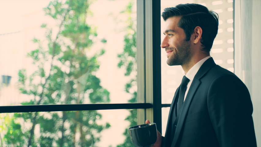 Handsome caucasian young man stands in the balcony with great views and drinks hot coffee or tea, sunshine, enjoying beautiful morning feeling happy Royalty-Free Stock Footage #1064959891