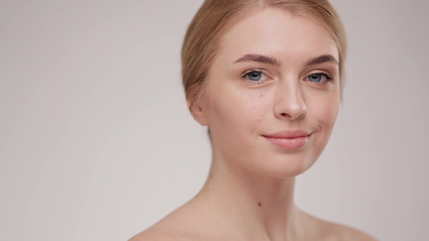 Slow motion portrait young woman uses creams of her face. Concept for fresh moisturized skin beautiful closeup cosmetic face happy healthy model. Young blonde hair woman take care of her skin. | Shutterstock HD Video #1064963266