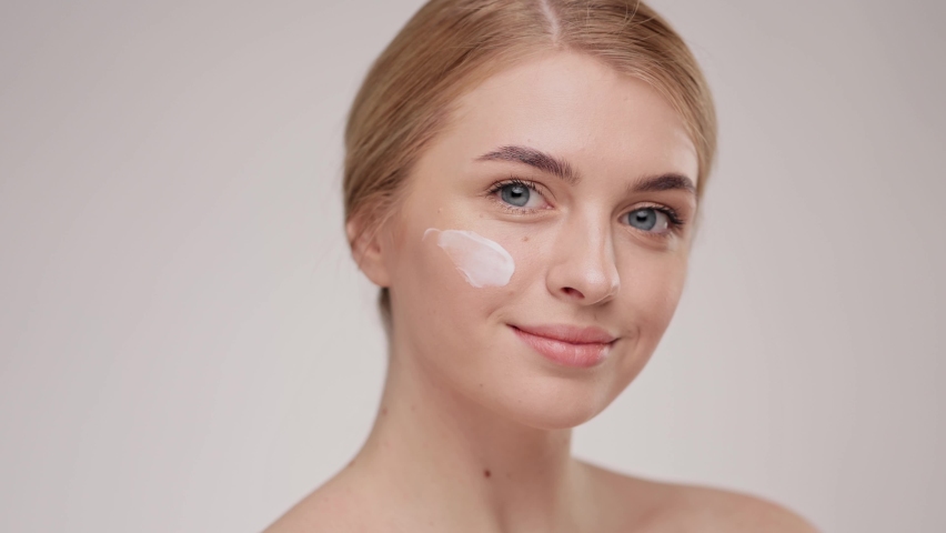 Slow motion portrait young woman uses creams of her face. Concept for fresh moisturized skin beautiful closeup cosmetic face happy healthy model. Young blonde hair woman take care of her skin. Royalty-Free Stock Footage #1064963266