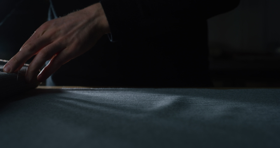 Cinematic macro shot of experienced tailor is controlling with hands fine quality fabric for creation custom haute couture apparel in tailoring workshop. Concept of handmade, couturier and tradition. Royalty-Free Stock Footage #1064965105