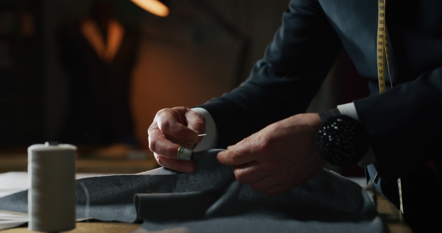 Cinematic shot of experienced tailor is sewing custom handmade high quality apparel in ancient luxury traditional tailoring workshop. Concept of industry, handmade, hand craft, couturier and tradition. Royalty-Free Stock Footage #1064965300