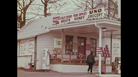 1970s: Front of Convenience Store. Storefronts along street. Map on United States, line around South is drawn. People ride in horse drawn carriage.