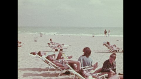 1970s: People relaxing on beach. People on bench on pier. Office building for lease.
