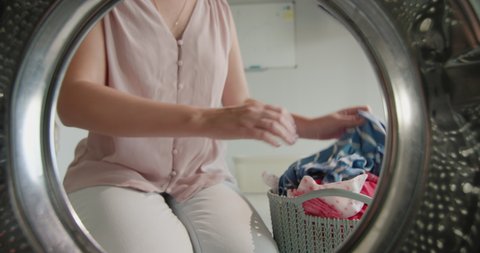 A woman puts colored underwear in a washing machine
