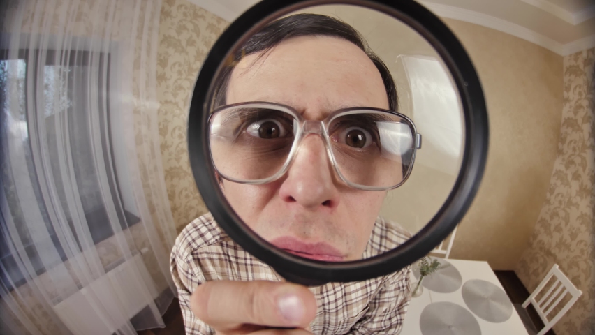 Funny man looks through magnifier glass