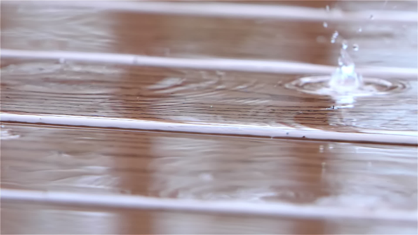 Rain drops falling on the wood plank floor of an exterior deck of a modern American suburban home Royalty-Free Stock Footage #1064985472