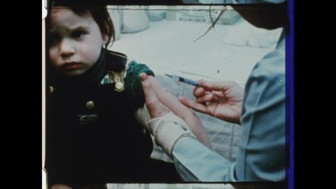 1980s Pittsburgh, PA. Mother holds Infant Girl as Doctor Injects her with Polio Vaccine. 4K Overscan of 16mm Film Print