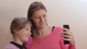Mother and her daughter have fun making selfies with mobile phone at home