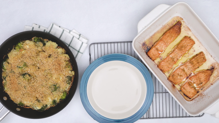 Baked salmon and vegetable casserole recipe. Chef serving delicious meal on plate. Cauliflower, broccoli casserole and baked salmon