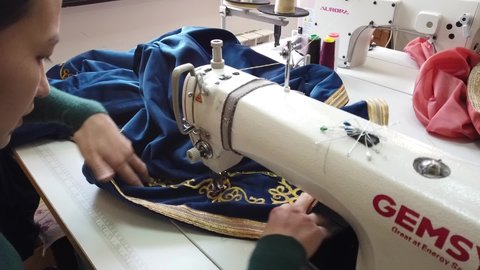 Almaty, Kazakhstan - 12.22.2020 : Employees of a small workshop are engaged in sewing Kazakh national clothes with patterns.