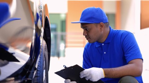 A car maintenance worker is checking the quality of the tires that are worn out, should they be replaced or not He takes care of the car for the customer.
