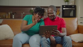 Happy attractive elderly retired african american couple sitting on couch, chatting and video conferencing online with children using digital tablet while enjoying leisure in domestic room. - Powered by Shutterstock - Get 15% off with code: PIKWIZARD15
