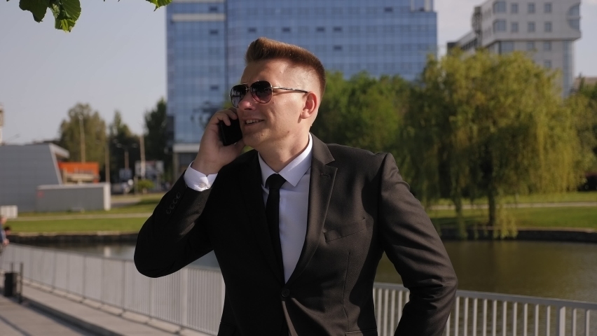 A successful businessman rides a gyro scooter in a Park to a business meeting and talks on the phone.
