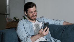 Close Up Of a man with Glasses Smiling Using a Smartphone Talking Online call with Friends.