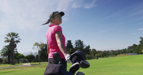 Caucasian woman playing golf carrying bag filled with golf clubs. golf cart and clubs in background. golf sports hobby healthy lifestyle.
