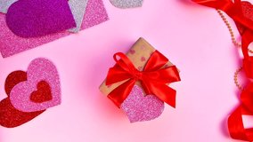 Valentine's Day or birthday presents. Valentine's Day gifts with a red paper heart on a wooden table. Girl wrapping red ribbon on gift box.