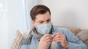 A man who is self-isolated and working from home because of a massive pandemic. A man holding a thermometer to measure body temperature. - Powered by Shutterstock - Get 15% off with code: PIKWIZARD15