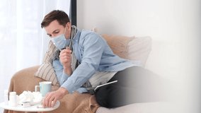 A man who is self-isolated and working from home because of a massive pandemic. A man holding a thermometer to measure body temperature. - Powered by Shutterstock - Get 15% off with code: PIKWIZARD15