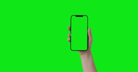 iPhone 12 Pro Max isolated on chroma key. Woman hand hold phone with a green screen in a vertical orientation portrait mode. Mockup for compositing. 2021 - USA, NY