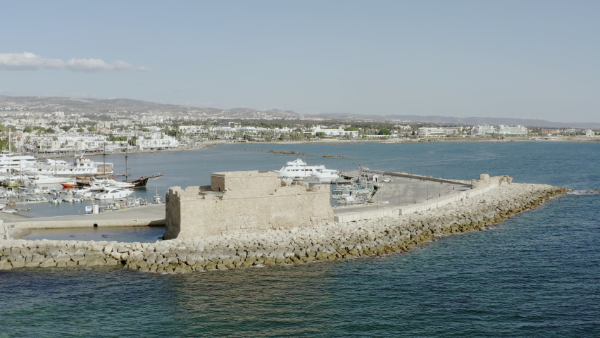 Drone flying over the old historic fort that stands on the shores of the Mediterranean Sea against the shoreline of which the waves crash. Aerial view Paphos Cyprus.