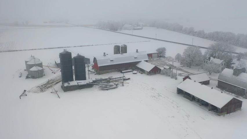 Aerial view of a farm in winter. Agricultural field covered with snow,  overcast cold misty weather
