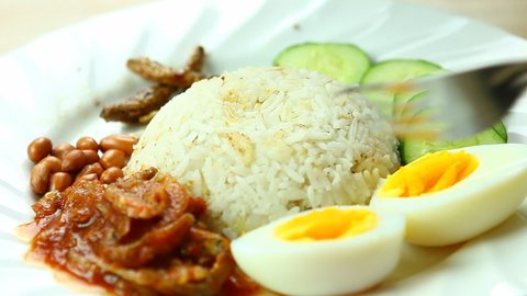 Man eating Nasi lemak (fragrant rice dish cooked in coconut milk and pandan leaf), Malaysian famous food.