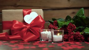 on the table there are two candles, a packed box and a bouquet of roses. Female hand laying down a valentine card in the form of a heart with the word love - Powered by Shutterstock - Get 15% off with code: PIKWIZARD15