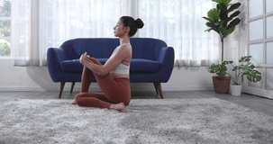 Young Asian woman doing yoga stretching yoga at home.