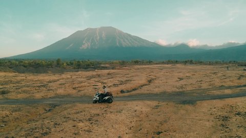 Active lifestyle people on a motorcycle exploring the amazing nature of Bali on background the largest active volcano Agung. Bali, Indonesia. 4K Aerial view