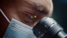 Ultra Macro Close Up Footage of a Male Scientist Wearing Medical Mask and Looking into the Microscope. Microbiologist Working on Molecule Samples in Modern Laboratory with Technological Equipment. - Powered by Shutterstock - Get 15% off with code: PIKWIZARD15