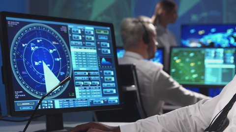 Workplace of the air traffic controllers in the control tower. Diverse team of aircraft control officers works using radar, computer navigation and digital maps. Aviation concept.