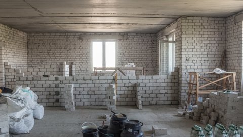 Builders laying brick walls inside appartment with professional tools timelapse. Workmen at work, bricklayers building wall, contractor and worker. Building materials around