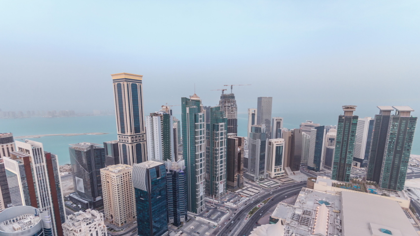 Skyline of the West Bay area from top in Doha day to night transition timelapse, Qatar. Illuminated modern skyscrapers aerial view from rooftop atevening after sunset. Traffic on the road Royalty-Free Stock Footage #1065060274