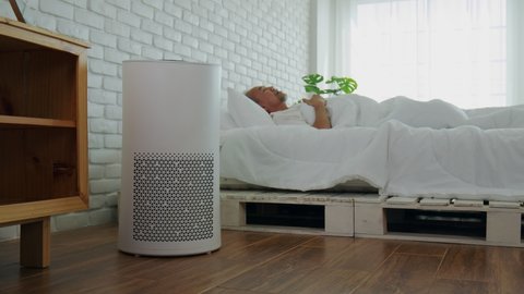 Elderly sleep with Air purifier in cozy white bed room for filter and cleaning removing dust PM2.5 HEPA in home,for fresh air and healthy life,Air Pollution Concept