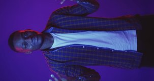 Young african american man dancing in neon lights background, having fun, video for vertical story, slow motion