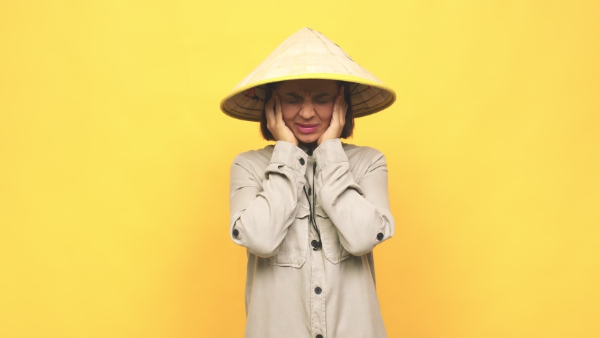 Young latin woman with vietnamese  hat covering ears with hands