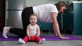 Yoga with children. A young mother is doing yoga, and the baby is sitting near the mat with a toy in his hands. The concept of home training and yoga with children.