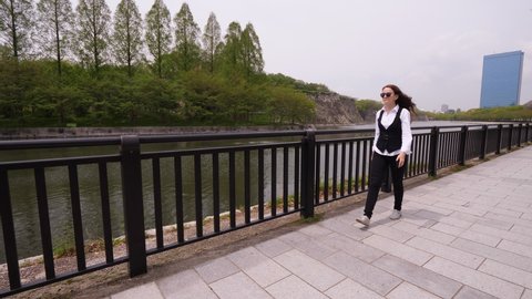 Business lady walk at embankment of Osaka Castle outer moat. European woman have free time during duty trip to Japan, take quick look at city landmarks