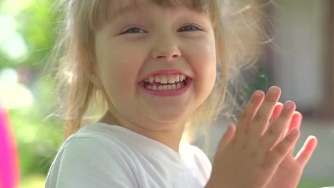 Little Girl Clapping hands and laughing outdoors. Cute three years old child enjoying nature outdoors. Healthy carefree kid playing outside in summer park. Full HD 1080p High speed camera, slow motion