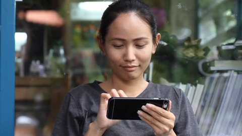 Asian girl playing smartphone, Woman use of mobile phone in cafe. Young Woman Using Smartphone While Sitting In Cafe. young woman typing a message on her smartphone