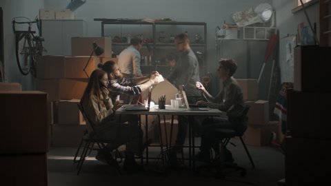 WIDE Young entrepreneurs working and packing orders inside garage. Launching their small business startup company from garage. Shot with 2x anamorphic lens