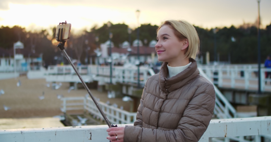 Cheerful young woman blogger makes a video report on her journey, tells her impressions of the trip by recording the broadcast on a mobile phone.