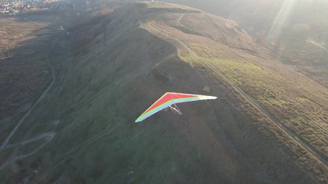 Camera follows colorful hang glider in the air. Aerial footage of extreme sport