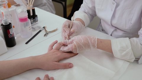 chelyabinsk. russia. dec 12. 2020. a spa body care master in a white robe and mask makes a manicure on another girl's hand, close-up in motion, only hands without a face are visible